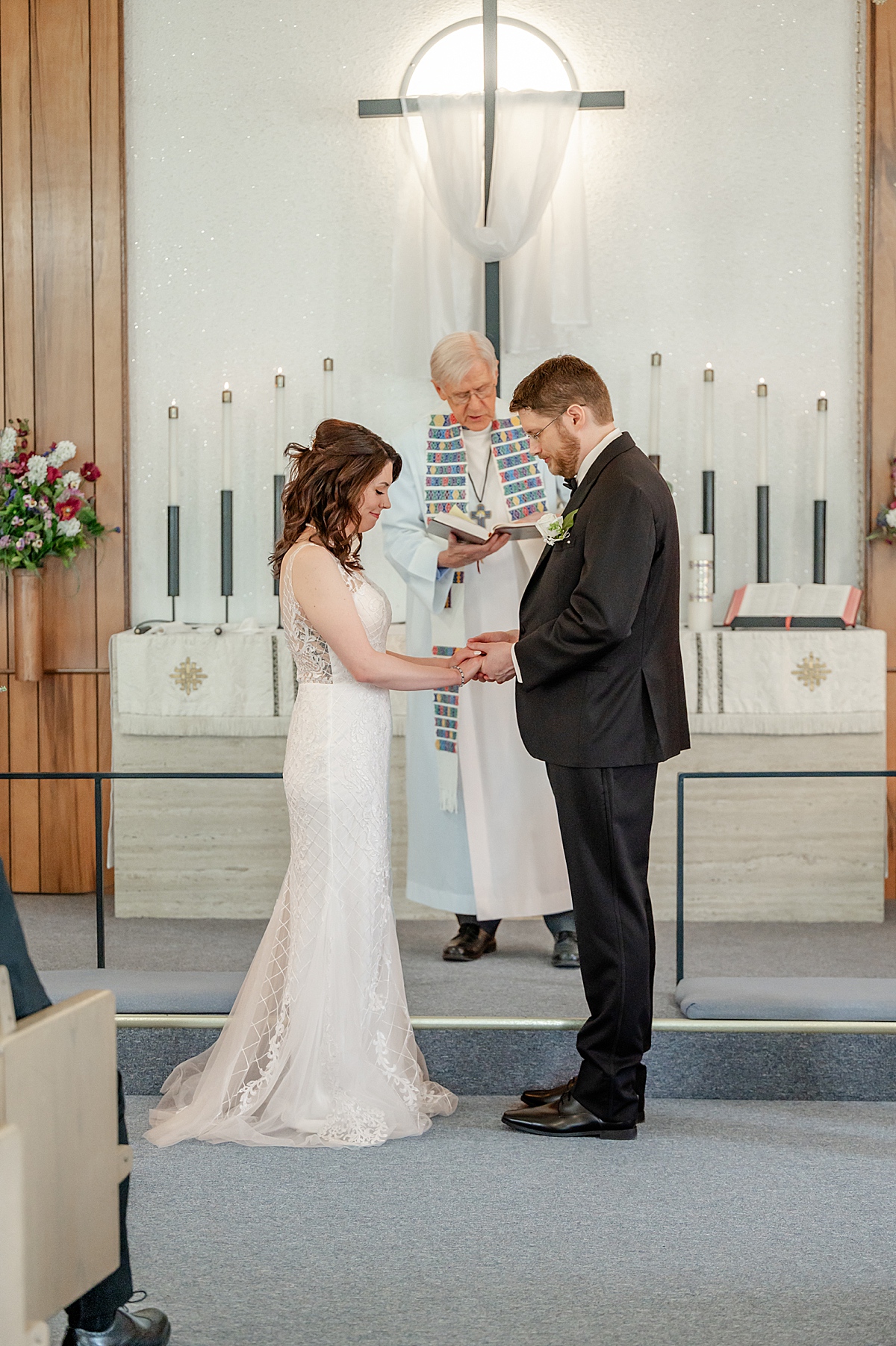 Bride and Groom holding hands in prayer at the front of the church.