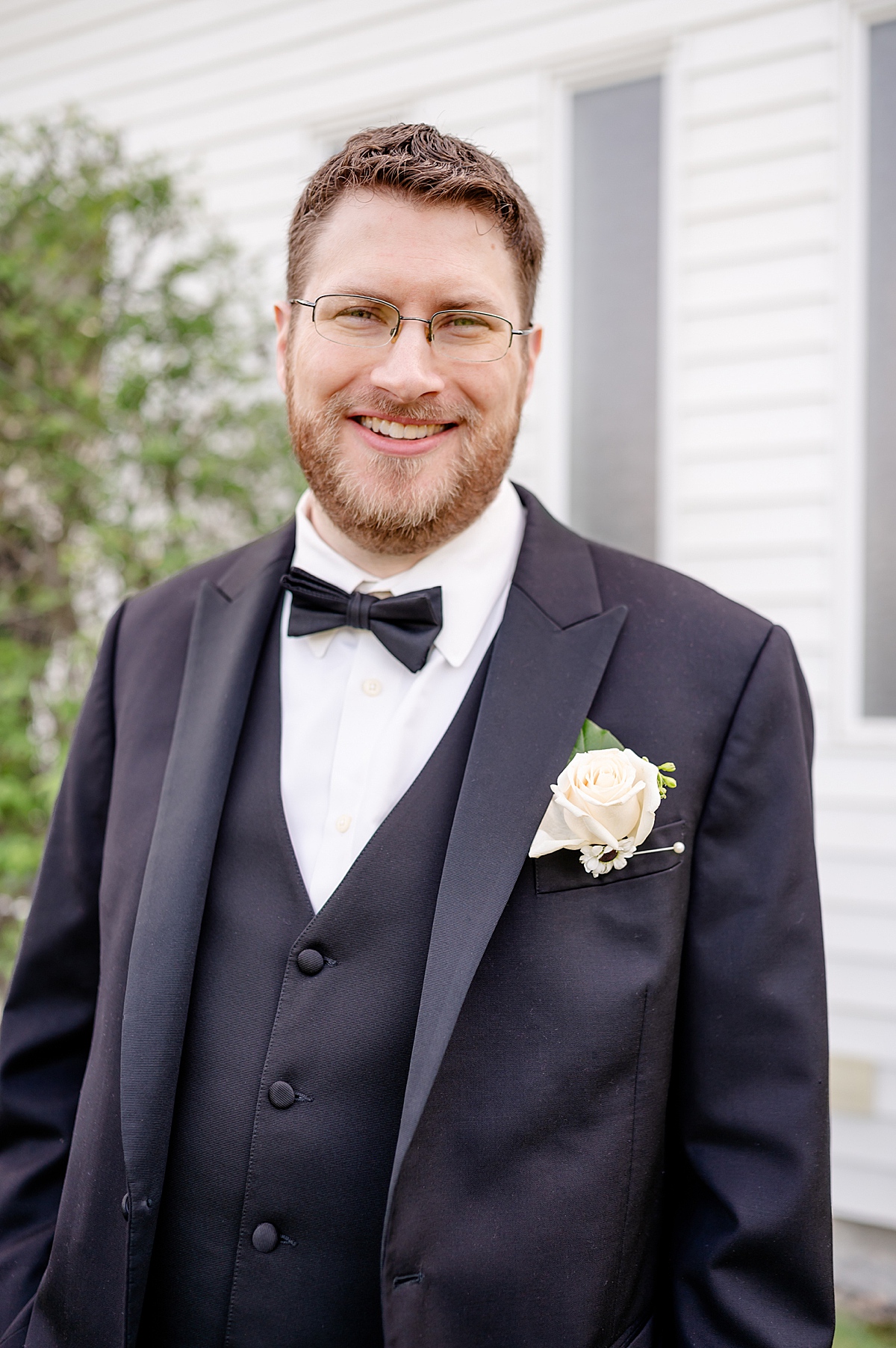 Portrait of the groom standing in front of a white church.