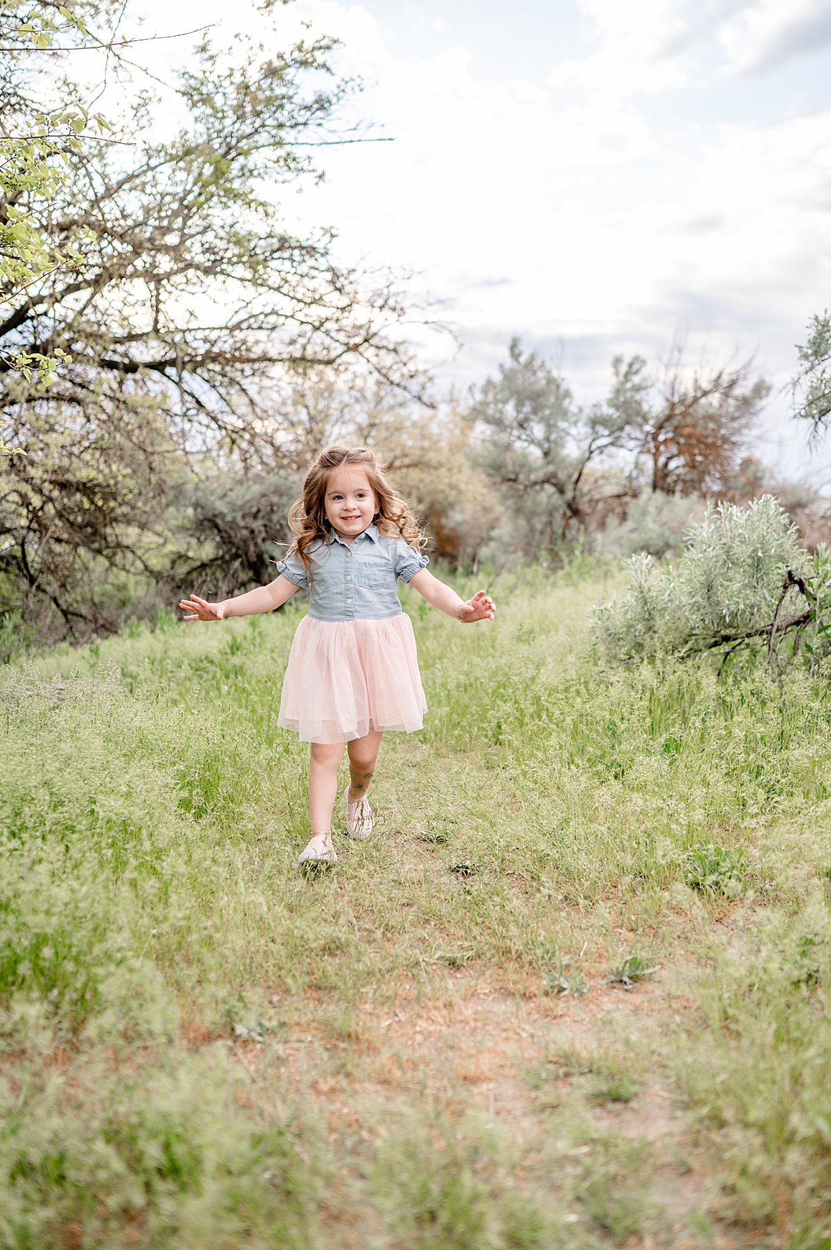 Little girl in a dress runs through the grass.